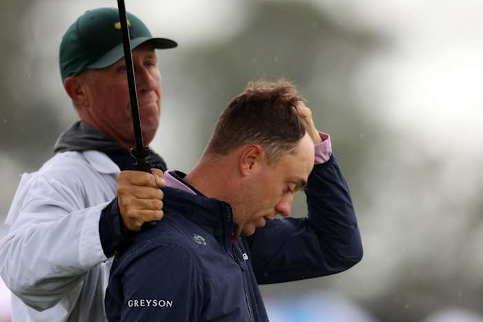 Justin Thomas of the United States and his caddie Jim 'Bones' Mackay react to his bogey on the 18th green during the continuation of the weather delayed second round of the 2023 Masters Tournament at Augusta National Golf Club on April 08, 2023 in Augusta, Georgia.